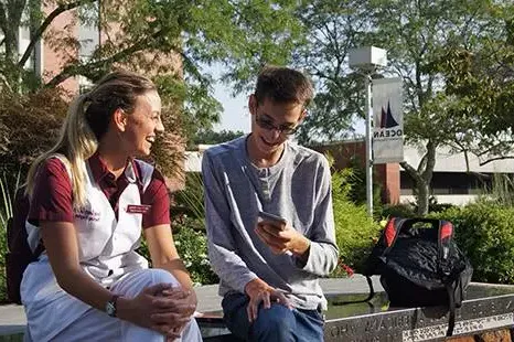 A male and female student laughing on campus